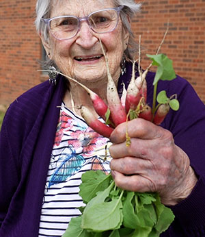 Female Veteran holding up Radishes.